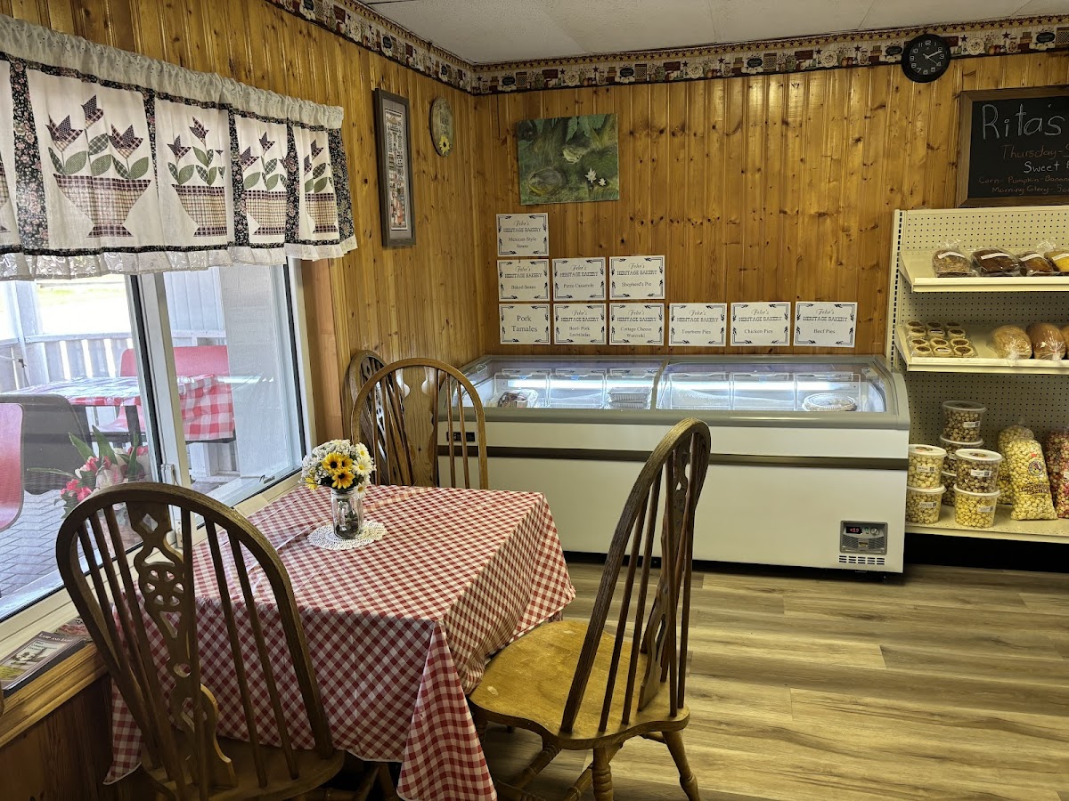Cozy interior of Fehr's Heritage Bakery with red-checkered tablecloth, wooden chairs, ice cream display, and bakery shelves