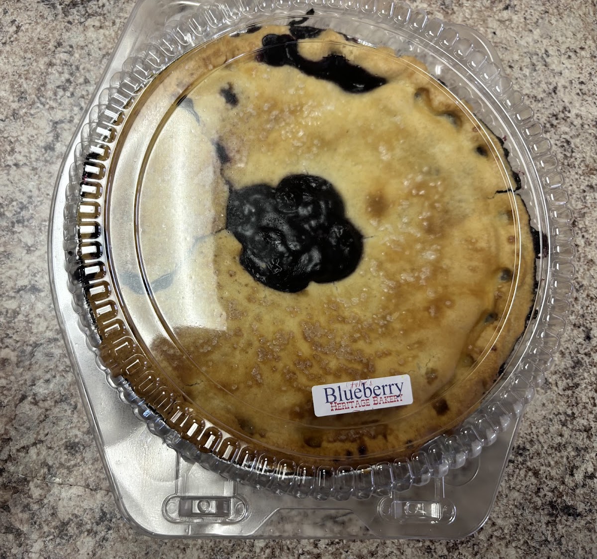 A fresh blueberry pie with golden lattice crust in a clear container