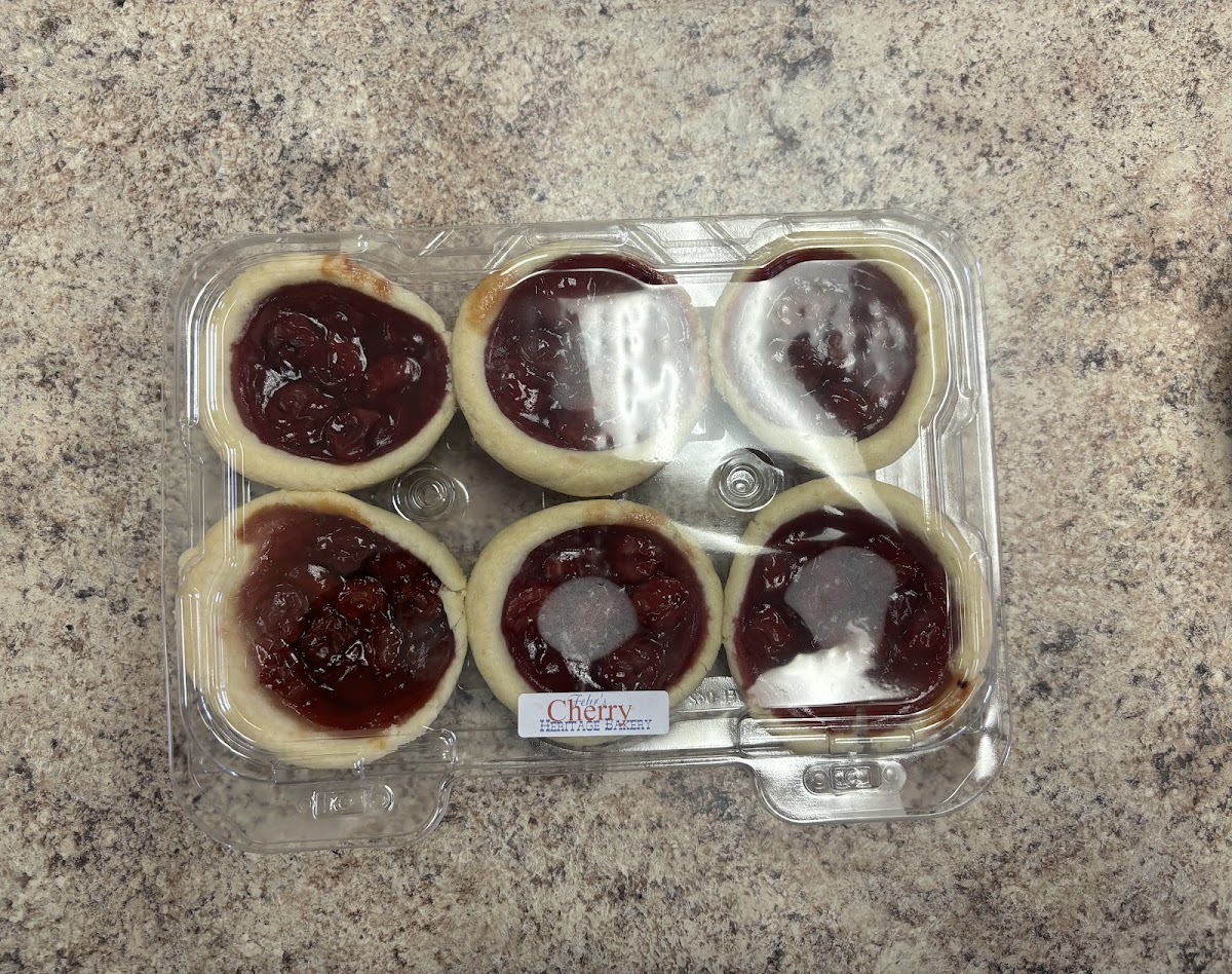 A six-pack of cherry butter tarts with deep red filling in golden pastry