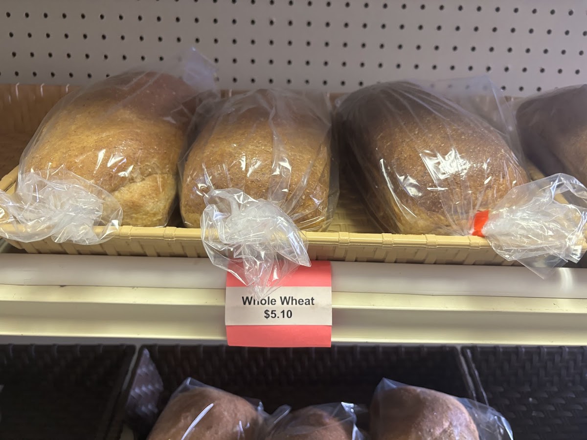 Loaves of fresh homemade whole wheat bread in bags on the bakery shelf